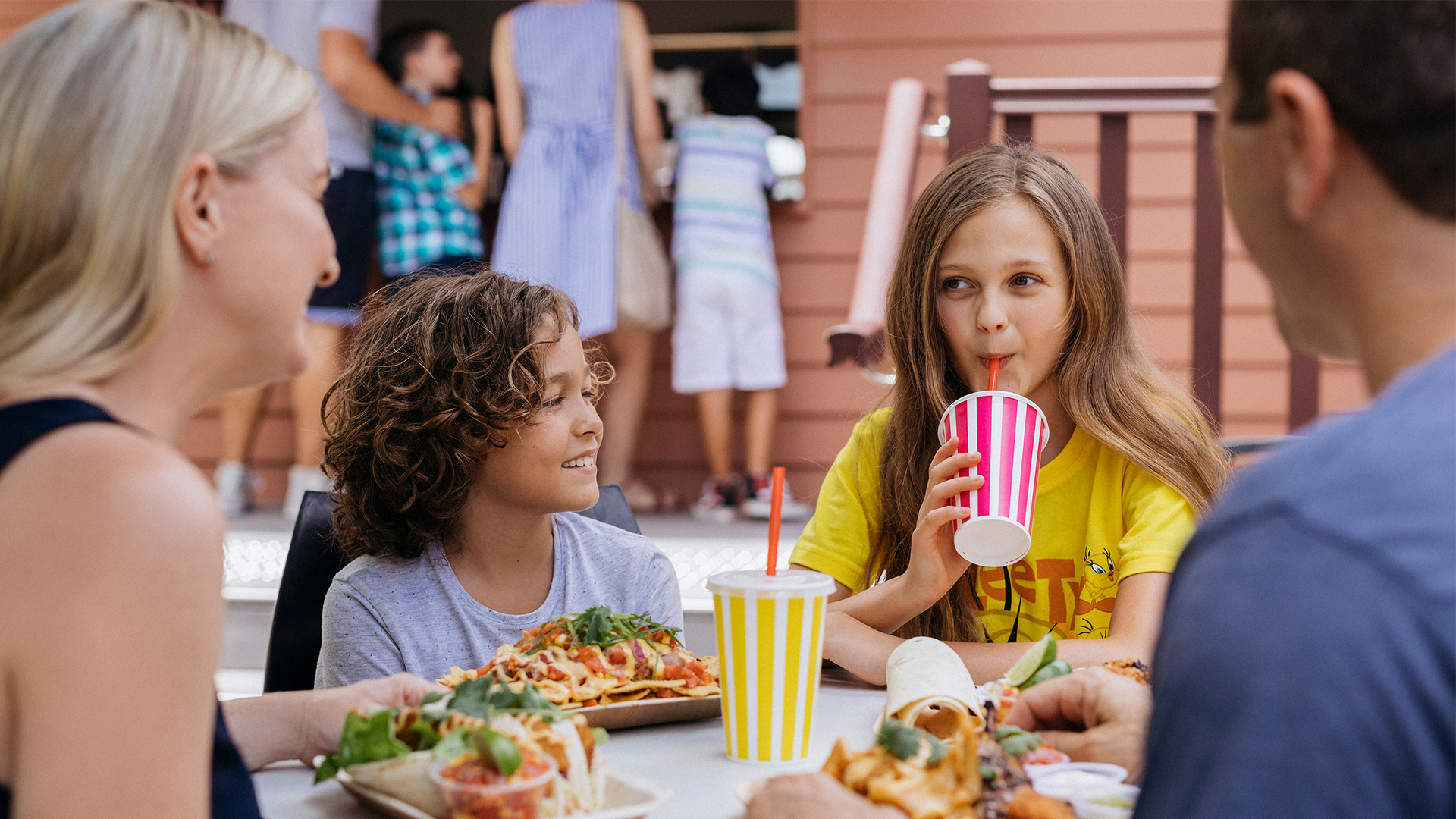 A family happily dining together at a table in Dirty Harry's Bar and Grill at Warner Bros. Movie World, enjoying delicious food and a relaxed atmosphere. food and beverage
