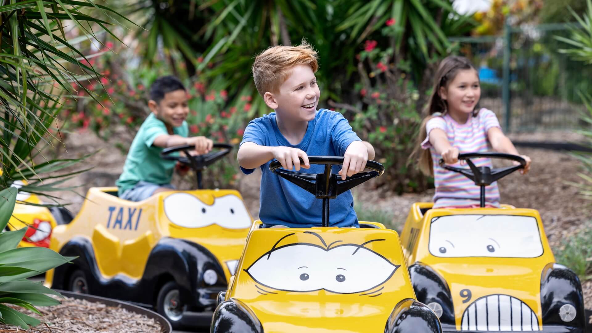 Excited children enjoying a ride on Speedy Gonzales' Tijuana Taxis at Warner Bros. Movie World, with colourful cars and joyful expressions, capturing the fun and excitement of the kids' ride experience