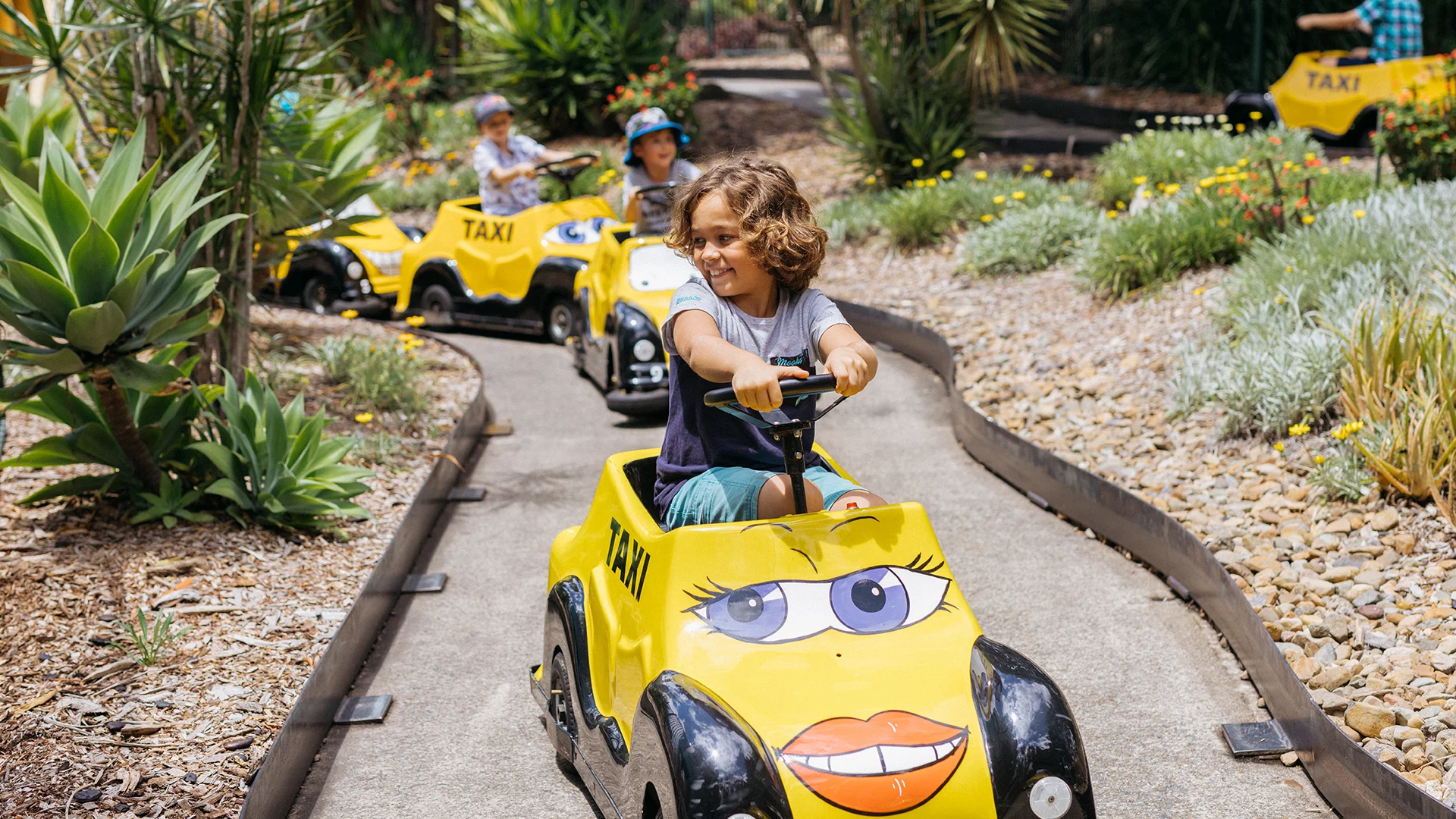 Excited children enjoying a ride on Speedy Gonzales' Tijuana Taxis at Warner Bros. Movie World, with colourful cars and joyful expressions, capturing the fun and excitement of the kids' ride experience