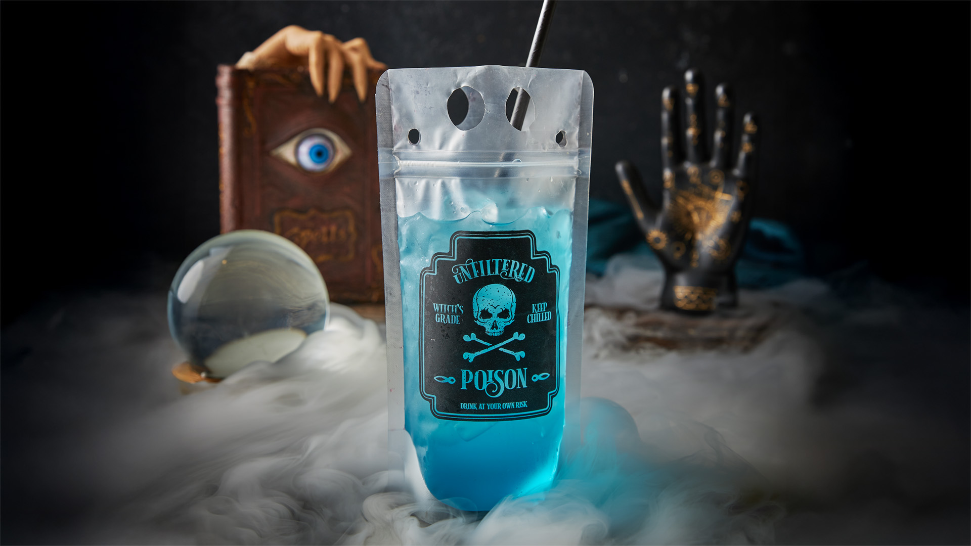 A blue drink in a pouch labeled "POISON" sits on a smoky surface, surrounded by a crystal ball, a creepy hand on a book with an eye, and a metallic skeletal hand in the background.