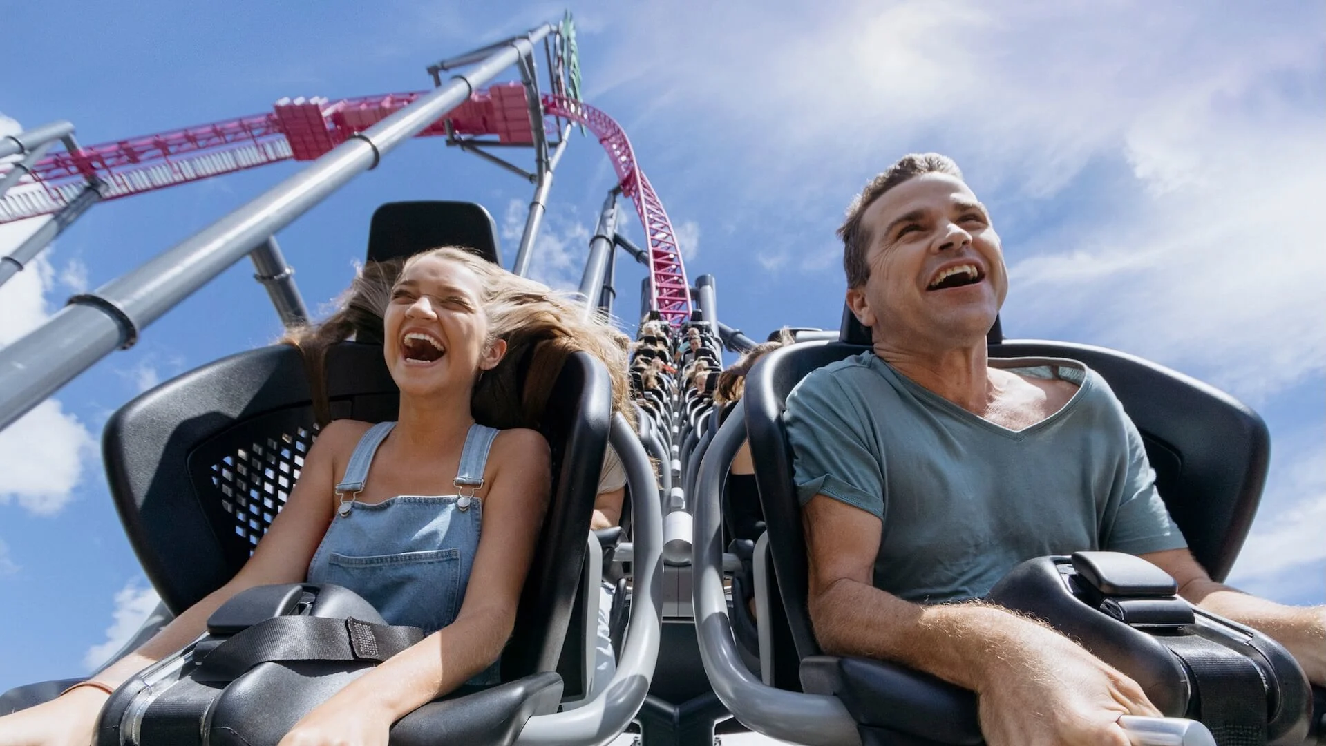 A couple enjoying a thrilling ride in the front seats of DC Rivals HyperCoaster, descending the first drop at Warner Bros. Movie World, with excitement and exhilaration on their faces