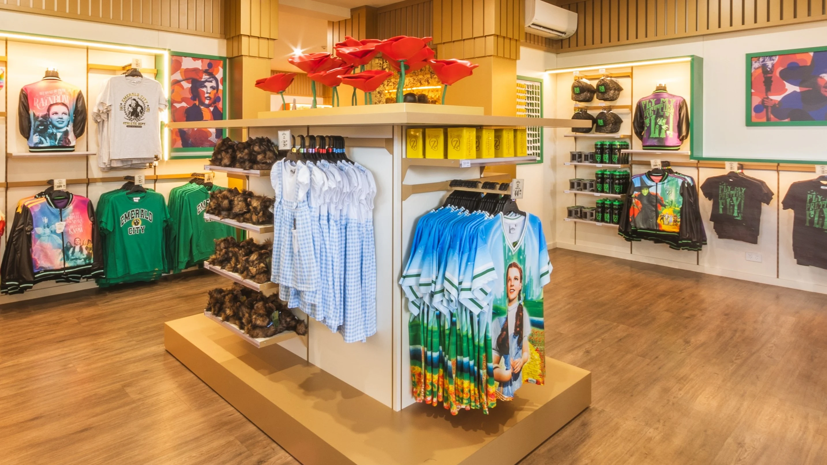A retail store interior displaying various T-shirts, shirts, and merchandise on racks and shelves, with bright lighting and wooden flooring. WOZ