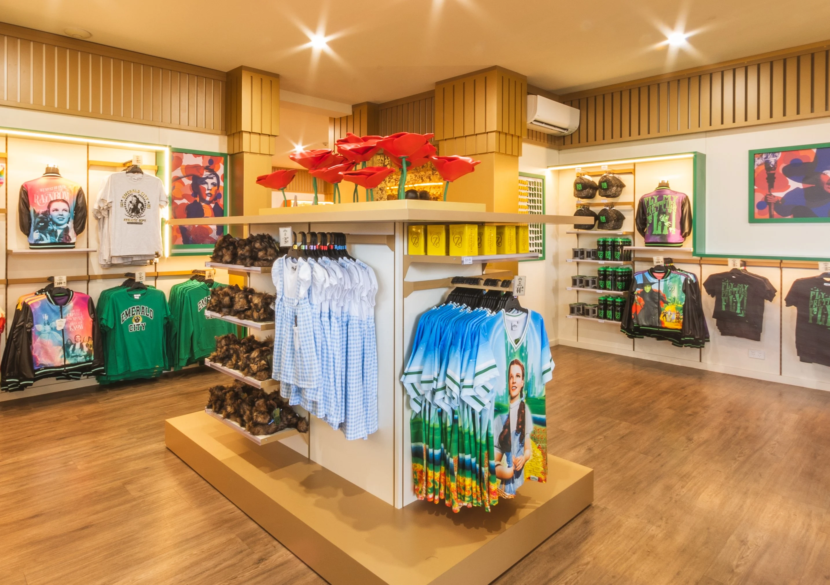 A retail store interior displaying various T-shirts, shirts, and merchandise on racks and shelves, with bright lighting and wooden flooring. WOZ