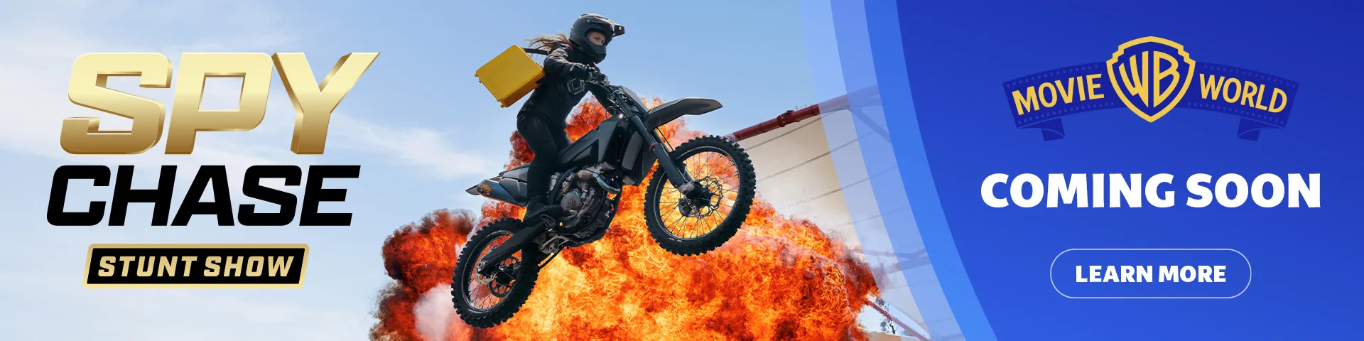 A stunt performer on a motorcycle jumps in front of an explosion, holding a yellow briefcase. Text reads "SPY CHASE Stunt Show" and "MOVIE WORLD COMING SOON." A button says "Learn More.