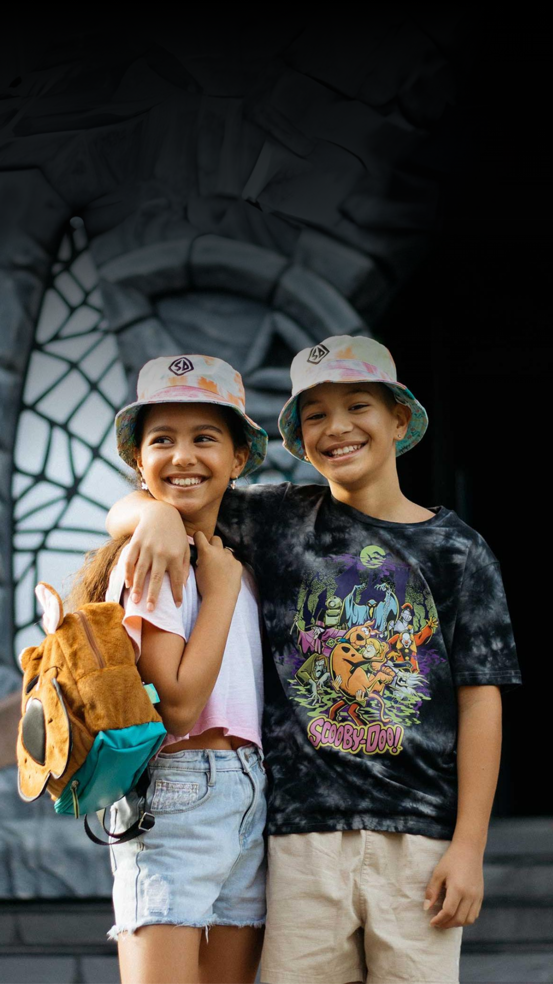 Two kids wearing Scooby-Doo merchandise, posing in front of Scooby-Doo Castle at Warner Bros. Movie World, adding to the fun and adventure of the theme park experience