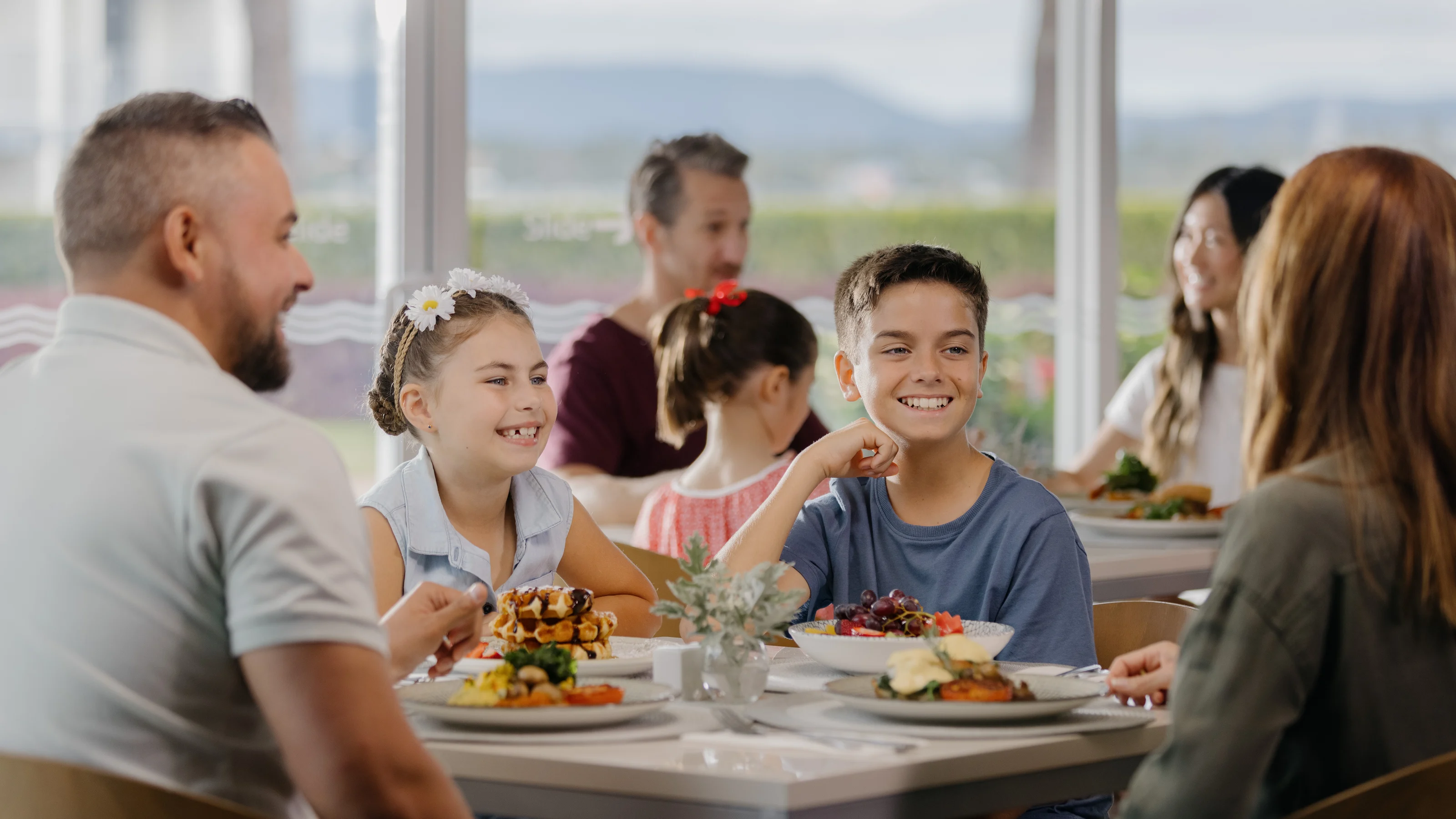 A family, including two parents and two children, sitting and smiling at a table at Shoreline Restaurant with plates of food.