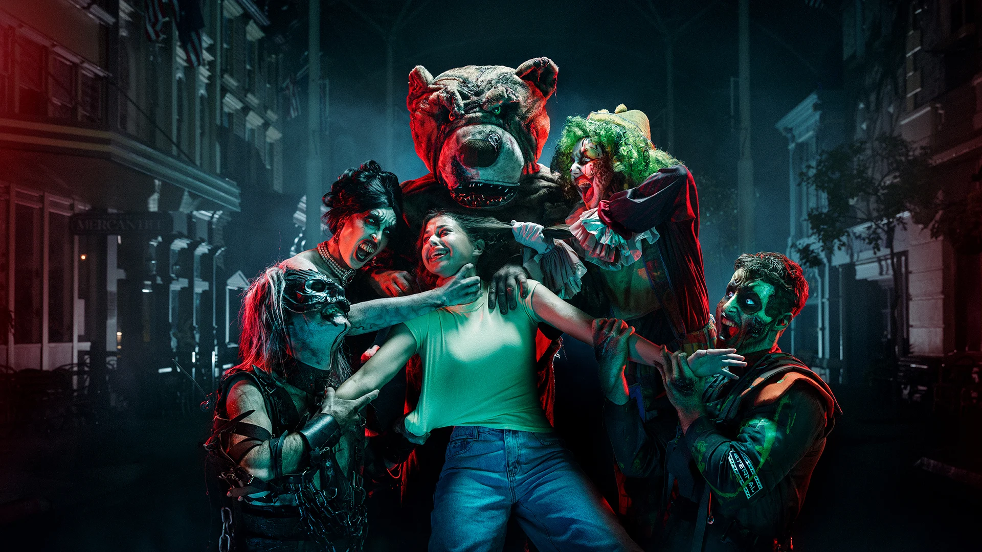 A person in a green tank top is surrounded by people in spooky costumes and face paint, including a bear mascot and clowns, on a dimly lit street at night, creating a tense, eerie atmosphere.