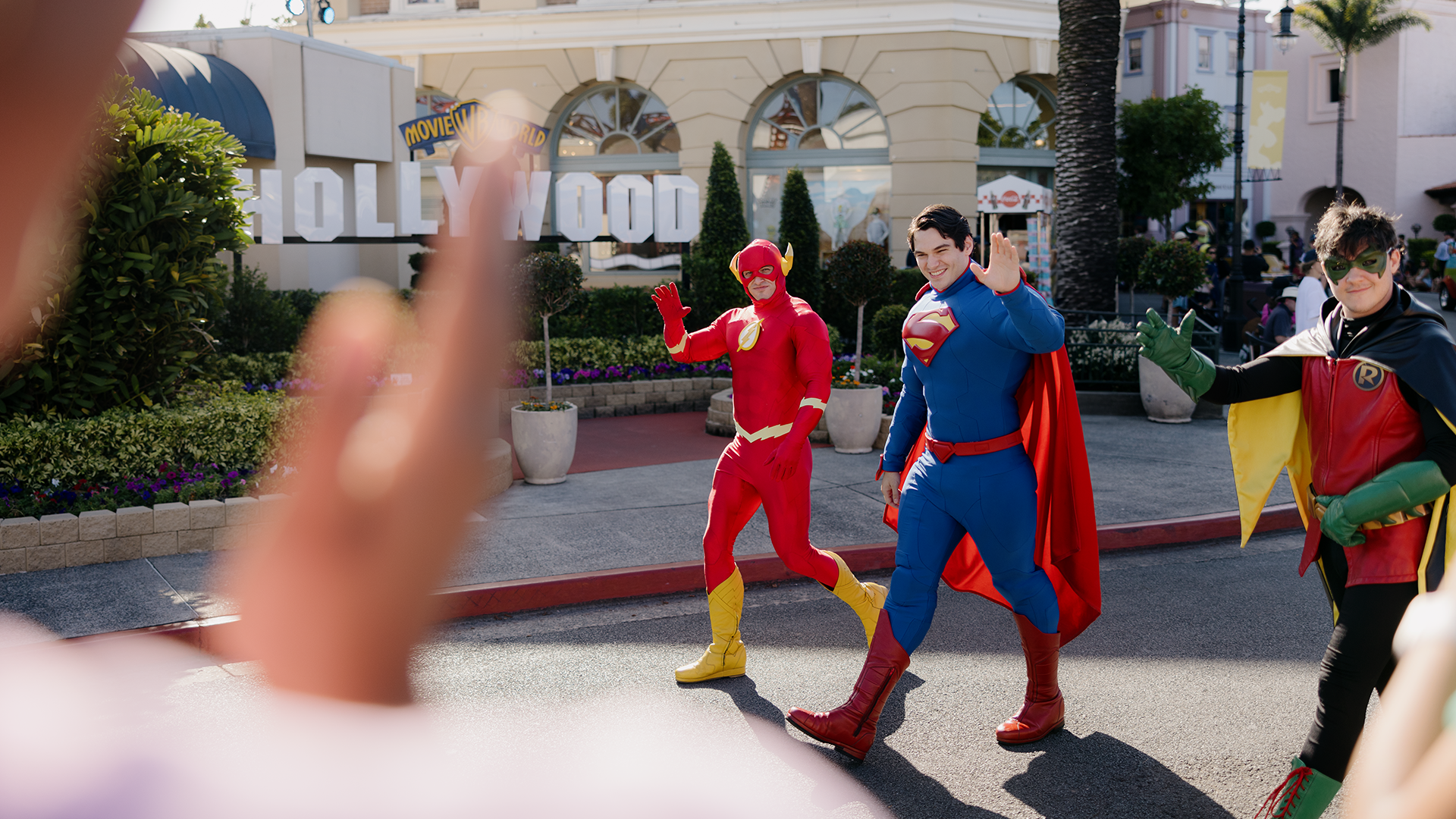 The Flash, Superman and Robin walking through Main Street, waving to the crowd, during the Star Parade at Warner Bros. Movie World