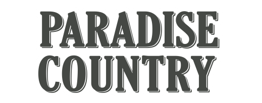 The image displays the words "PARADISE COUNTRY" in bold, uppercase, serif font with a white outline.