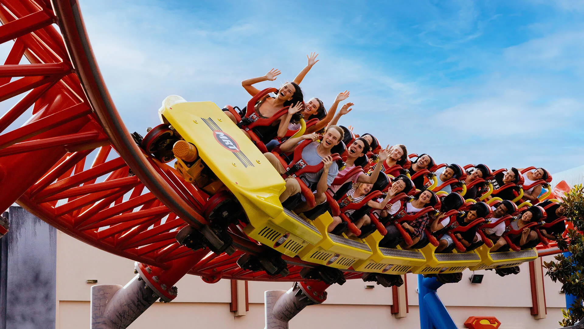 Excited riders with their hands up, enjoying the thrilling experience on the Superman Escape thrill ride at Warner Bros. Movie World, feeling the rush of high-speed twists and turns