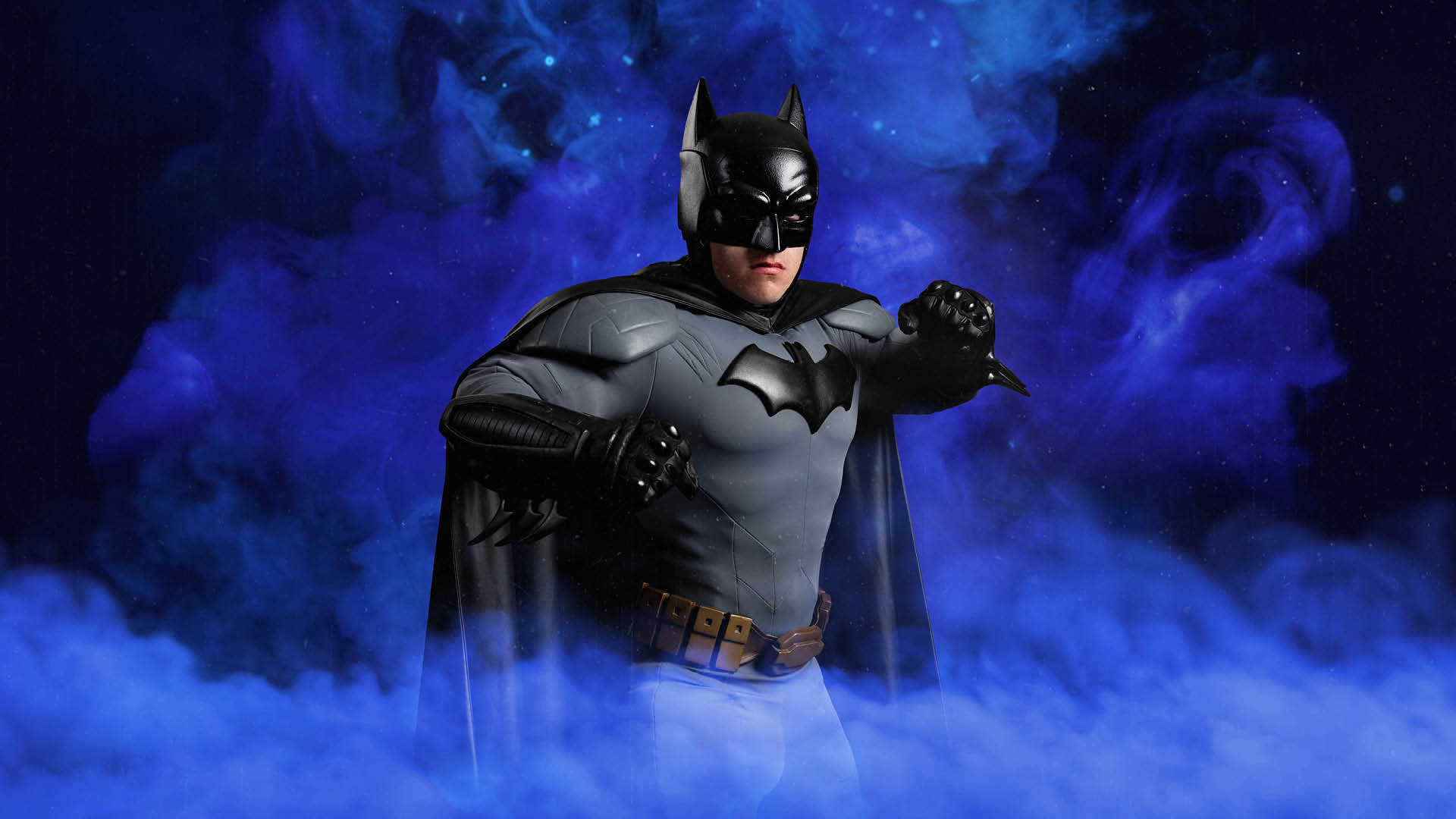 Person in a Batman costume poses with fists raised, standing against a swirling purple smoke background.