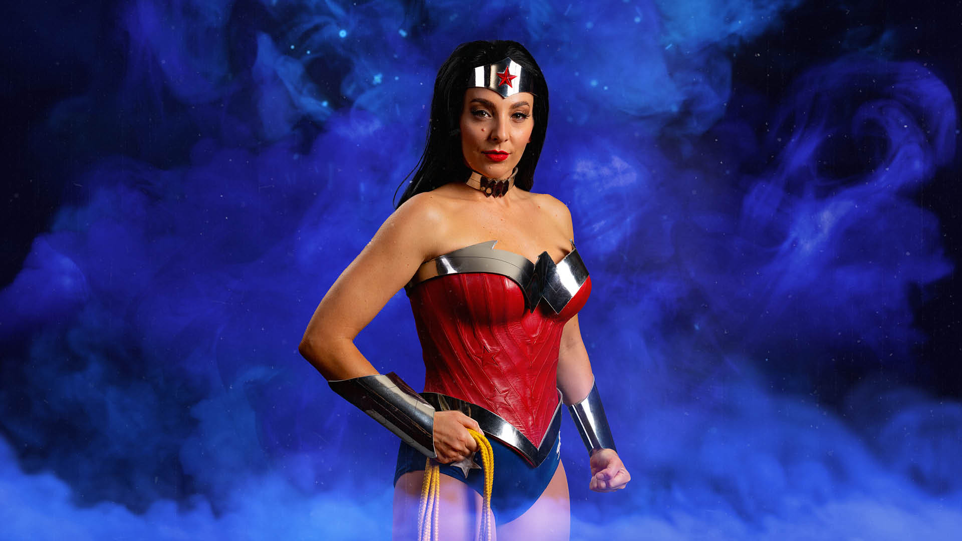 A person in a red and silver superhero costume poses confidently in front of a purple smoky background.