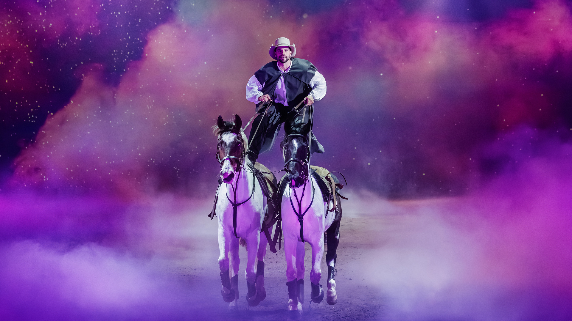 A person in a cowboy hat and costume stands with one foot on each of two white horses, riding through purple fog with a vibrant, colorful, starry sky in the background.
