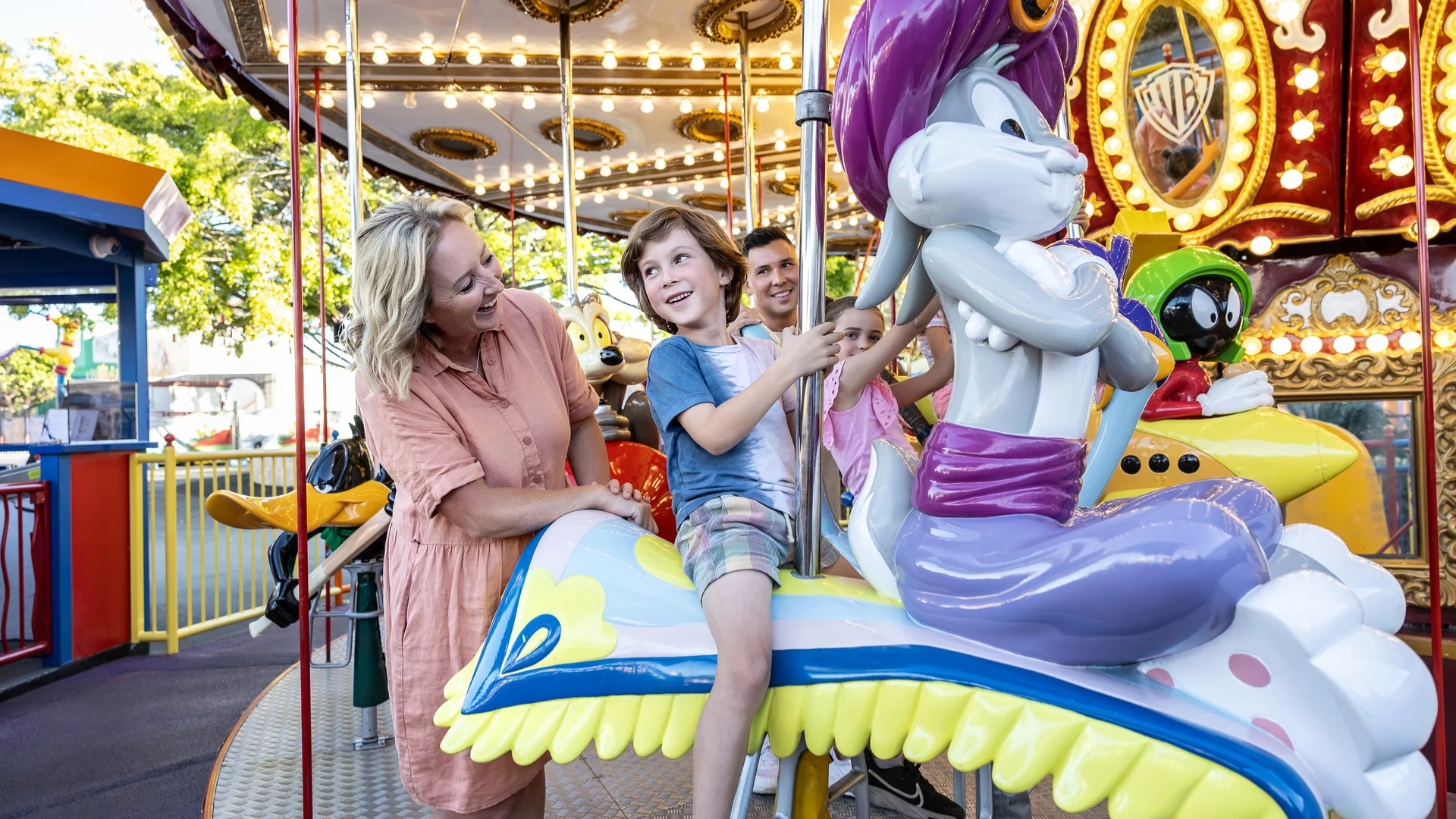 Children happily riding the Looney Tunes Carousel at Warner Bros. Movie World, enjoying a classic and colourful carousel experience with favourite Looney Tunes characters