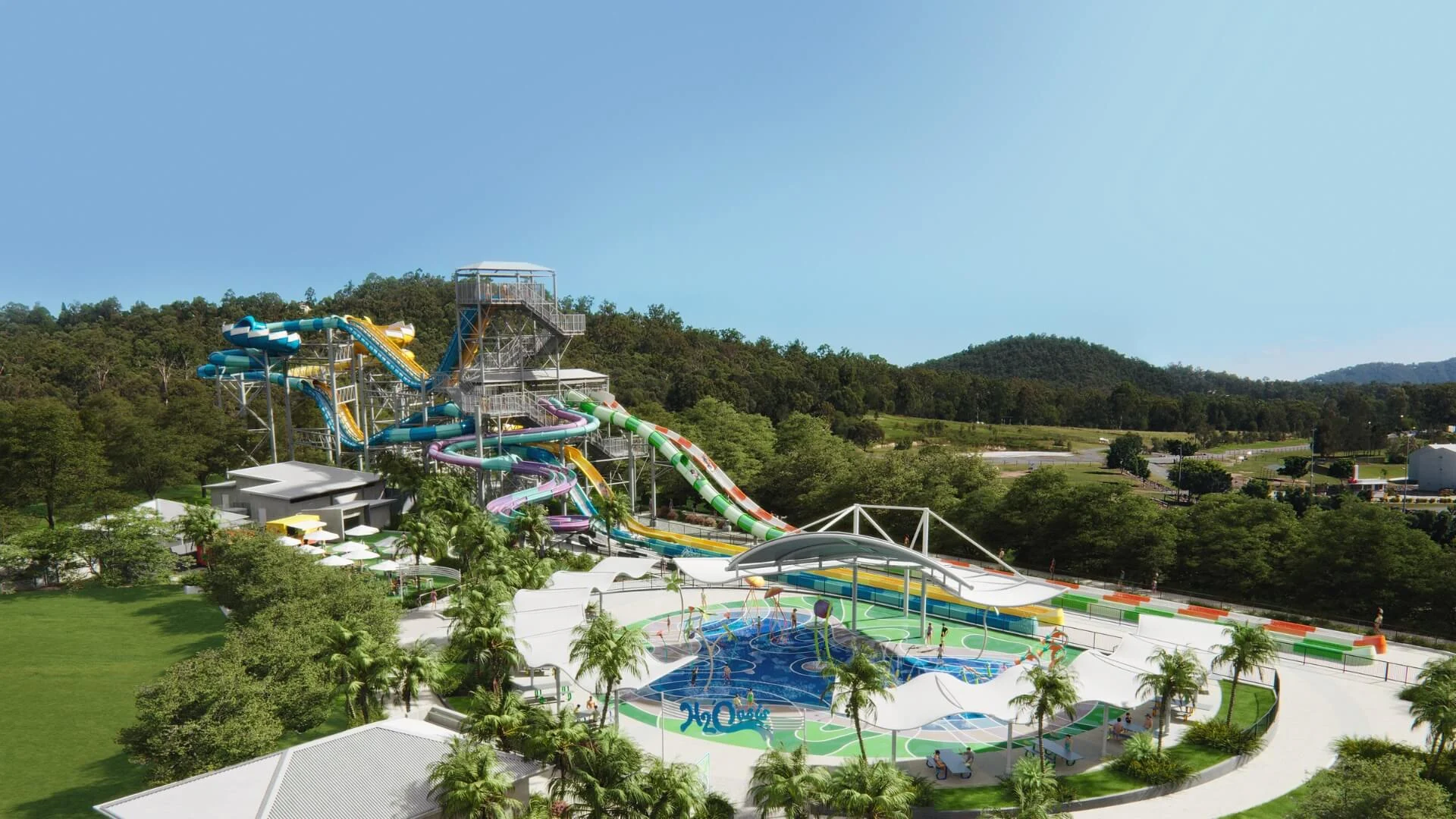 Wide view of the water slides and splash zone at Wet’n’Wild Gold Coast, featuring colourful twisting slides, shaded seating areas, and surrounding green hills