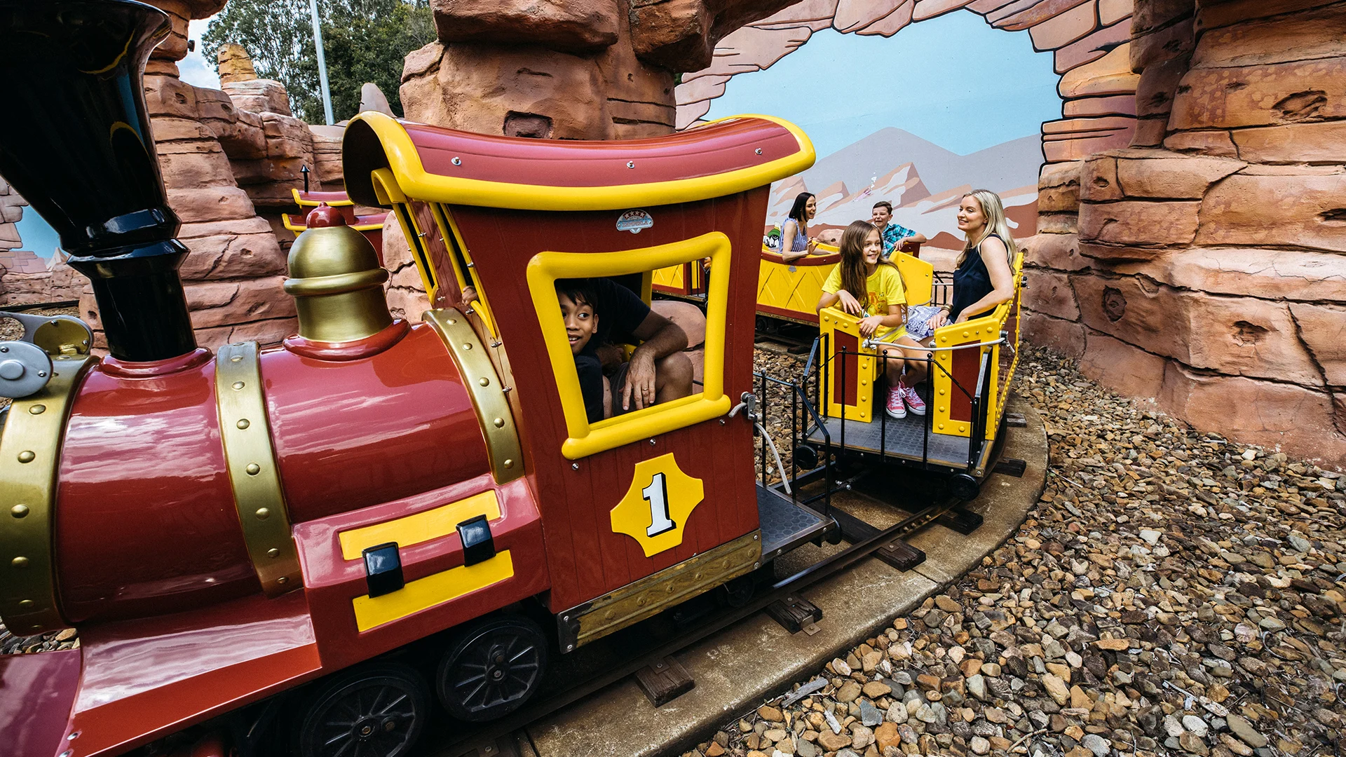 Families happily riding the Yosemite Sam's Railroad kids ride at Warner Bros. Movie World, enjoying a leisurely train adventure through themed landscapes