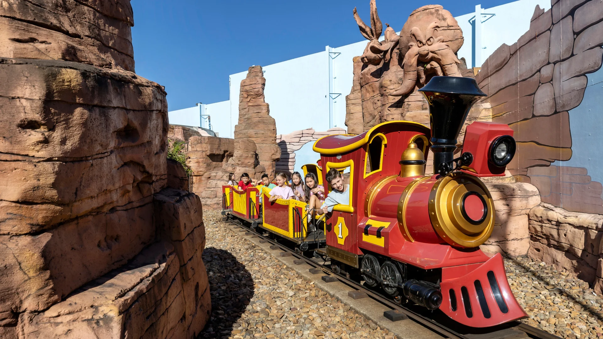 Families happily riding the Yosemite Sam's Railroad kids ride at Warner Bros. Movie World, enjoying a leisurely train adventure through themed landscapes