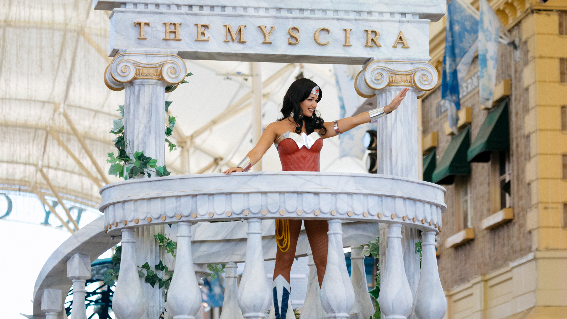 Wonder Woman standing on a float and waving to the crowd during the Star Parade on Main Street at Warner Bros. Movie World