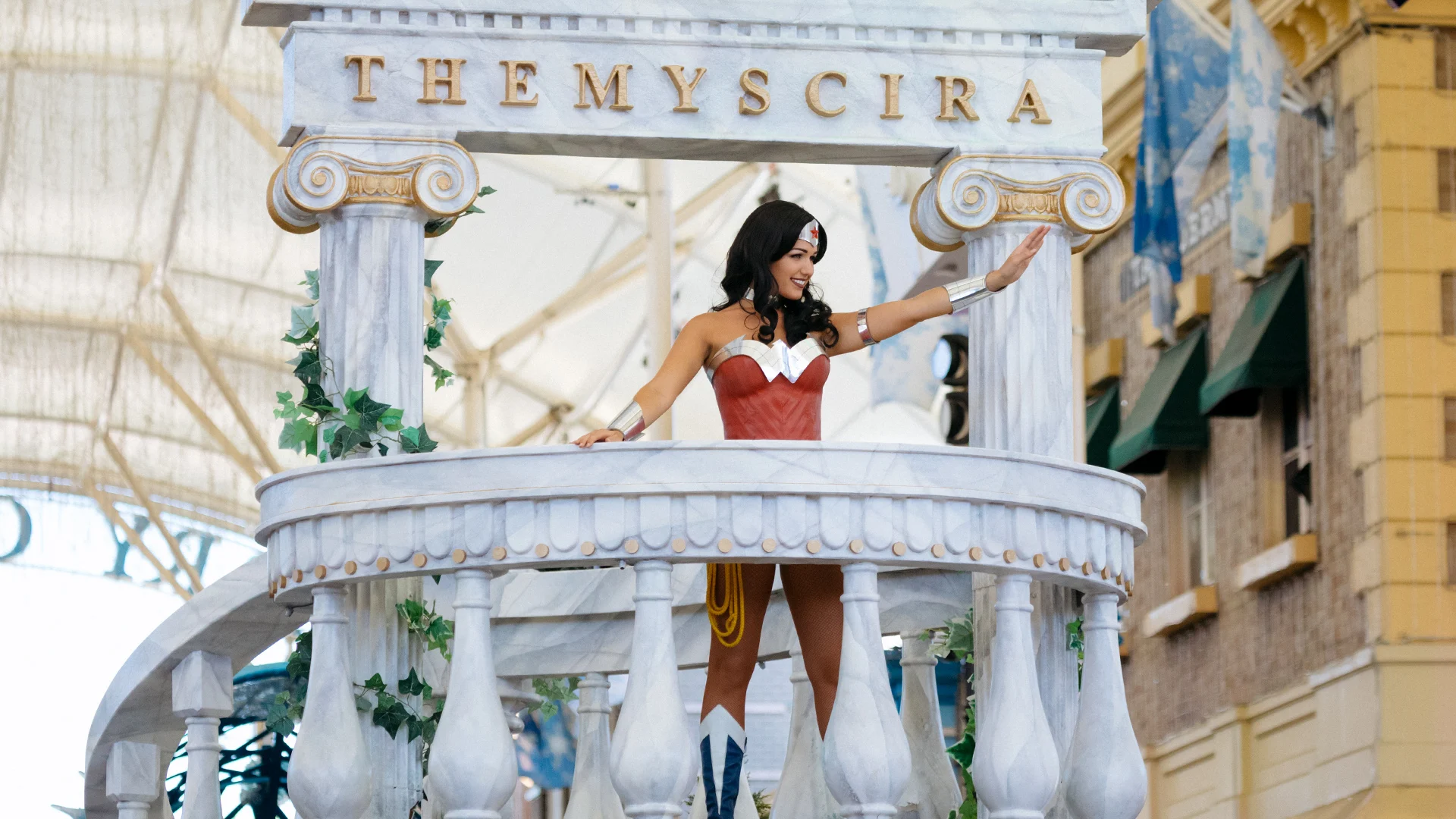 Wonder Woman standing on a float and waving to the crowd during the Star Parade on Main Street at Warner Bros. Movie World