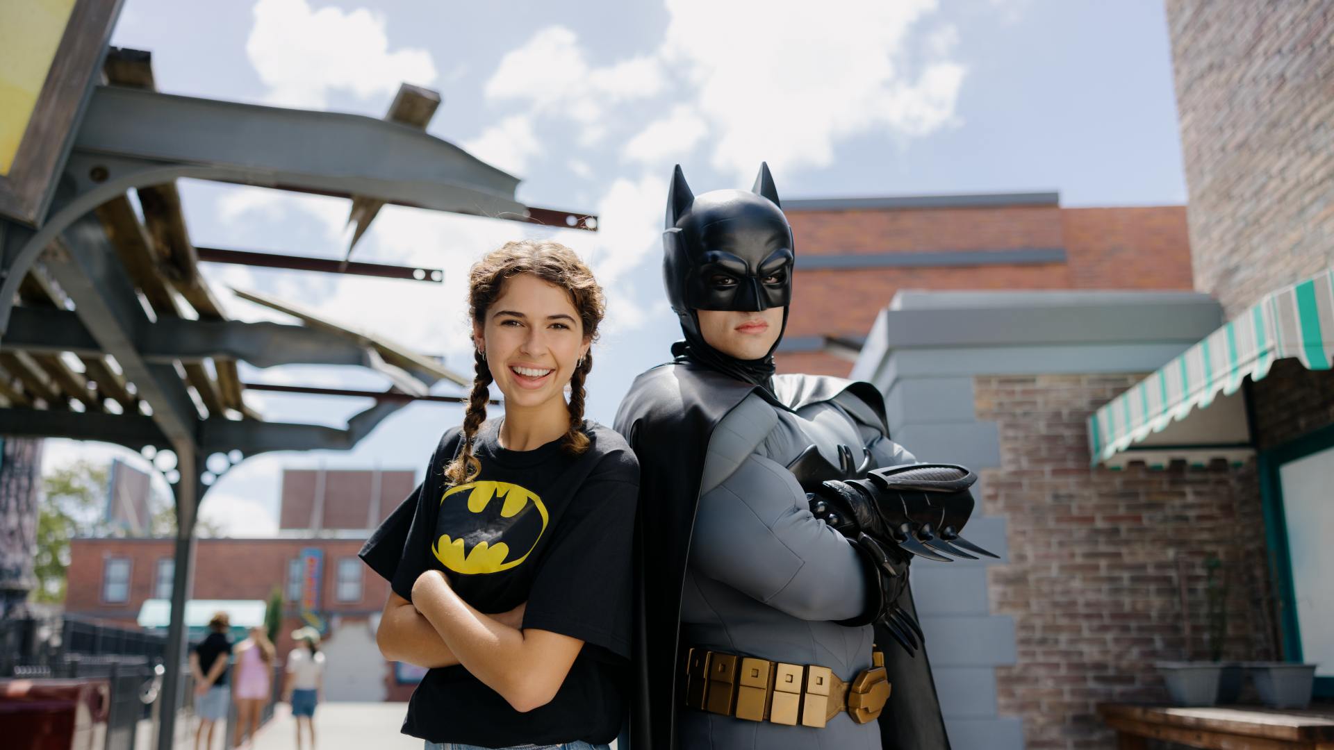 A teenage girl in Batman merchandise posing happily with Batman at Warner Bros. Movie World