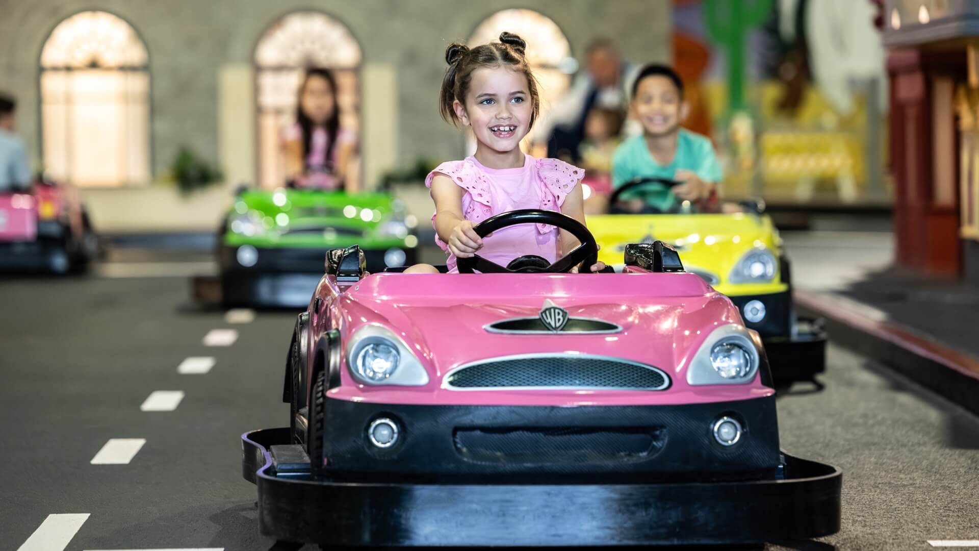 Children enjoying the Junior Driving School kids attraction at Warner Bros. Movie World, driving miniature cars around a scaled-down version of the theme park