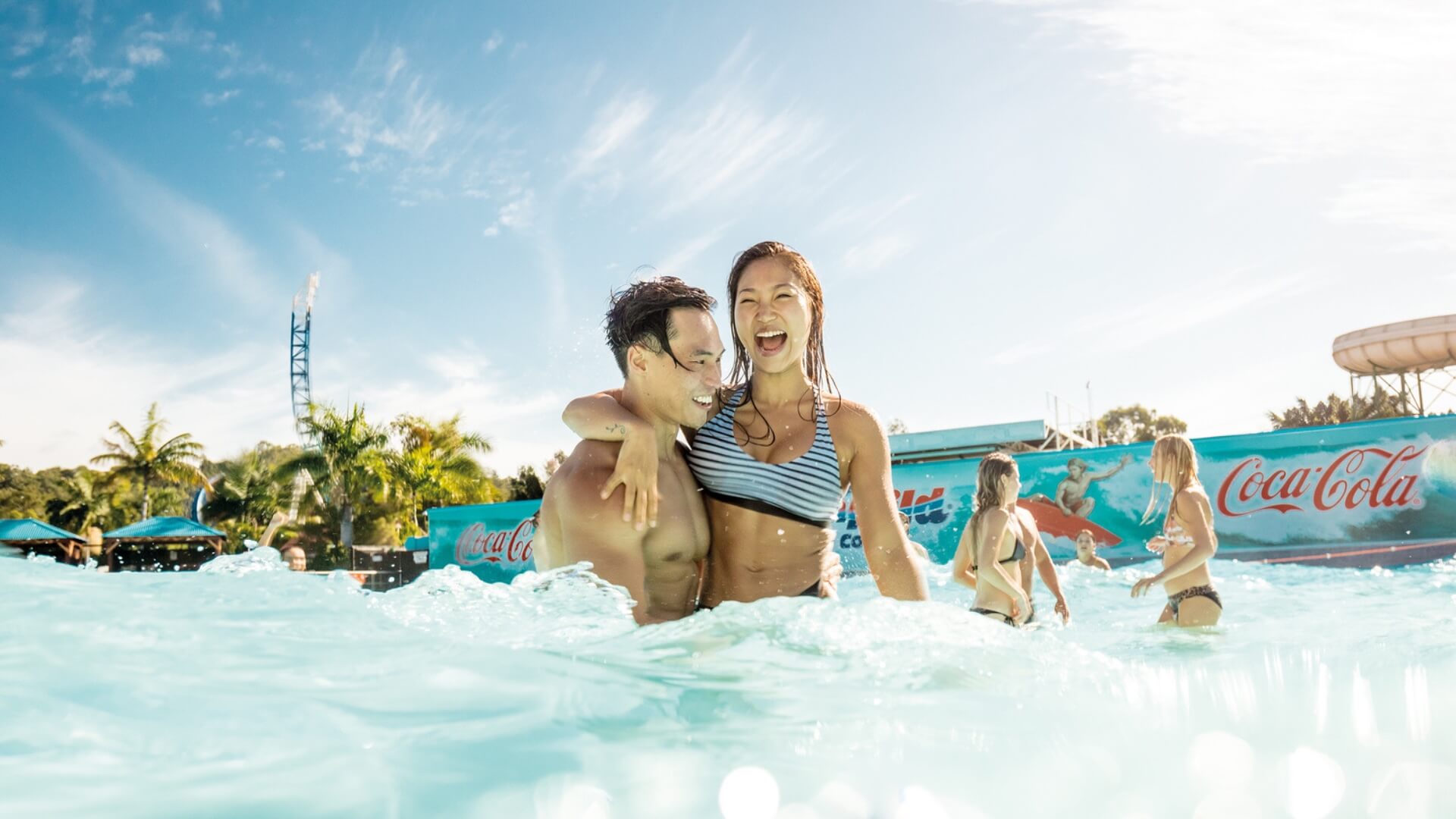 Couple enjoying the refreshing wave pool at Wet’n’Wild, surrounded by friends and sunshine on a fun summer day.