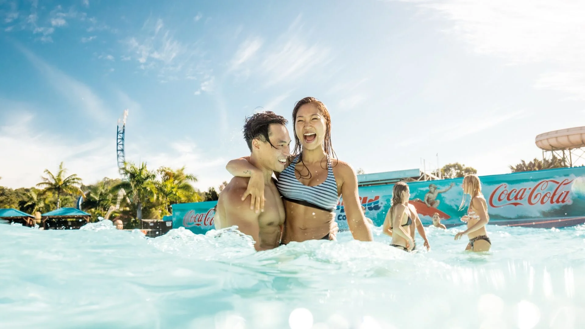 Couple enjoying the refreshing wave pool at Wet’n’Wild, surrounded by friends and sunshine on a fun summer day.