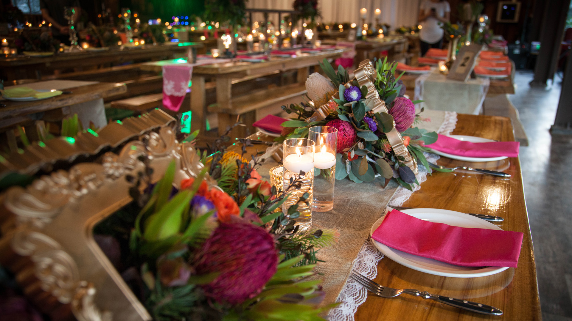 A close up of a table decorated with pink napery, Australian native flowers, and candles in a restaurant.