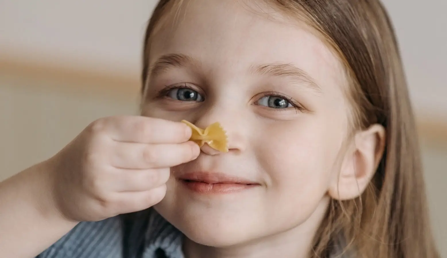 Girl Holding Piece of Barilla® Farfalle Pasta to Her Face