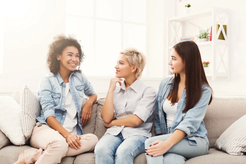 Trois jeunes filles souriantes assises sur le canapé