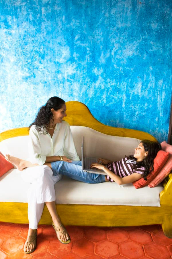 Maman et fille avec ordinateur portable sont assis sur un canapé