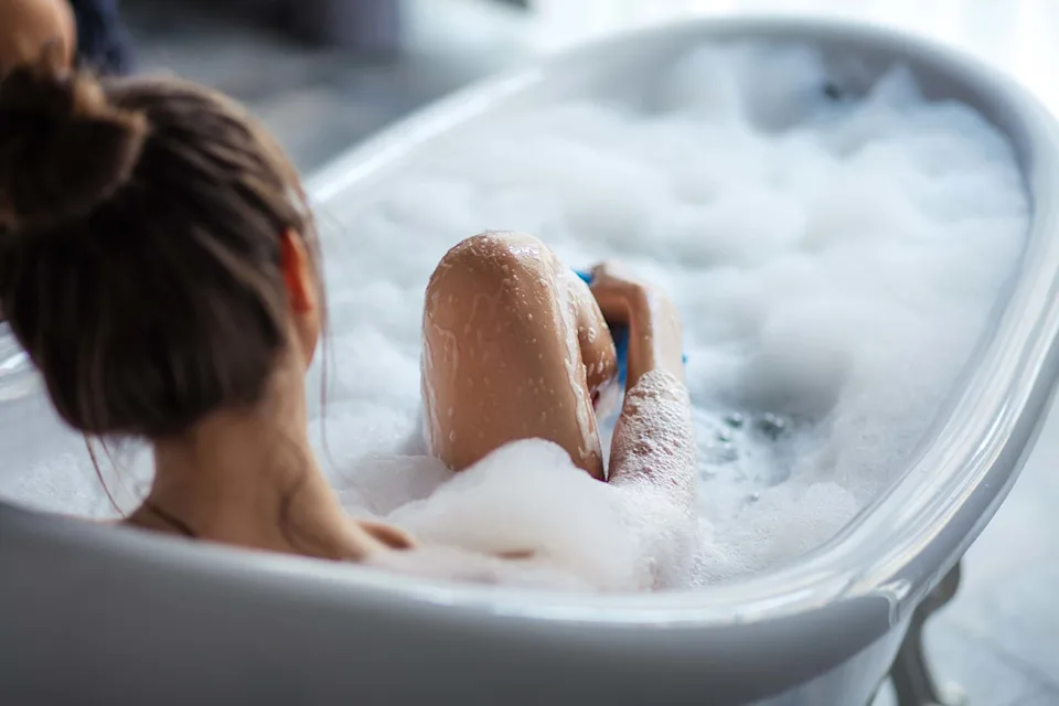Jeune femme prenant un bain avec de la mousse