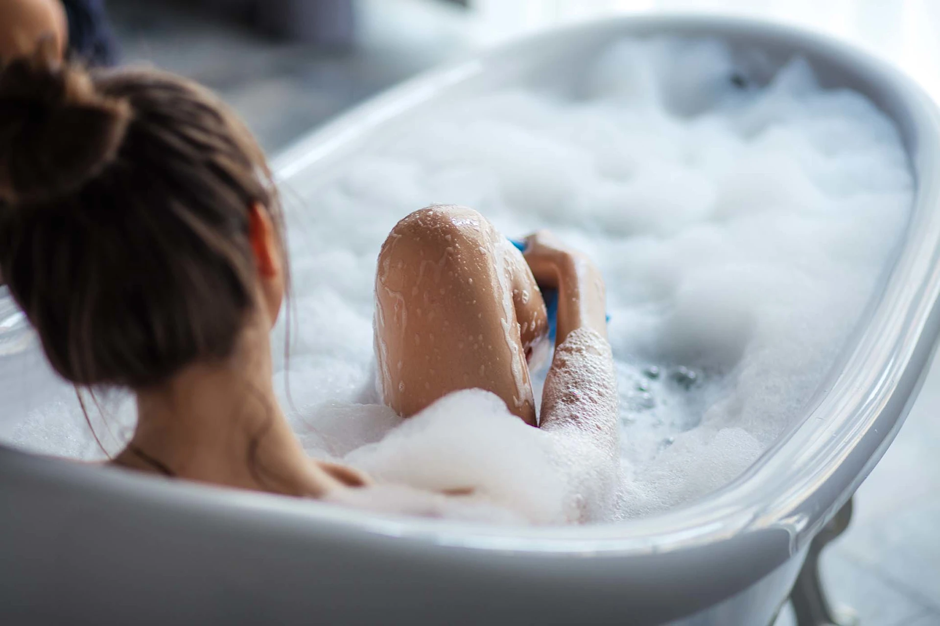 Jeune femme prenant un bain avec de la mousse