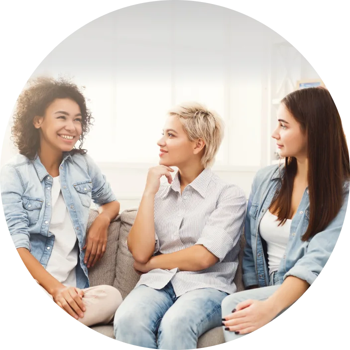 Trois jeunes filles souriantes assises sur le canapé