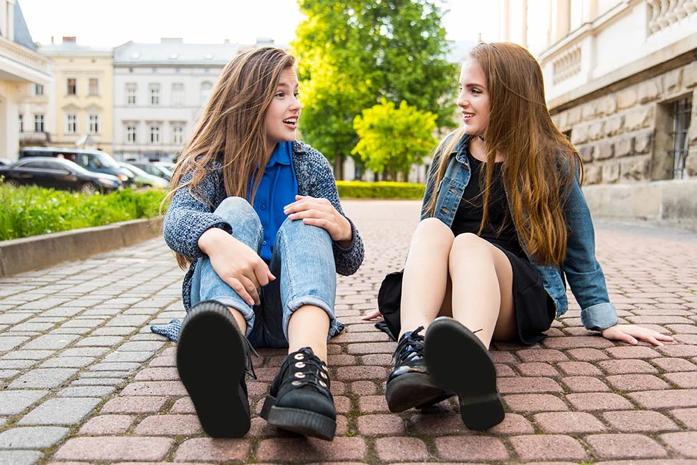 Deux jeunes filles assises sur le trottoir