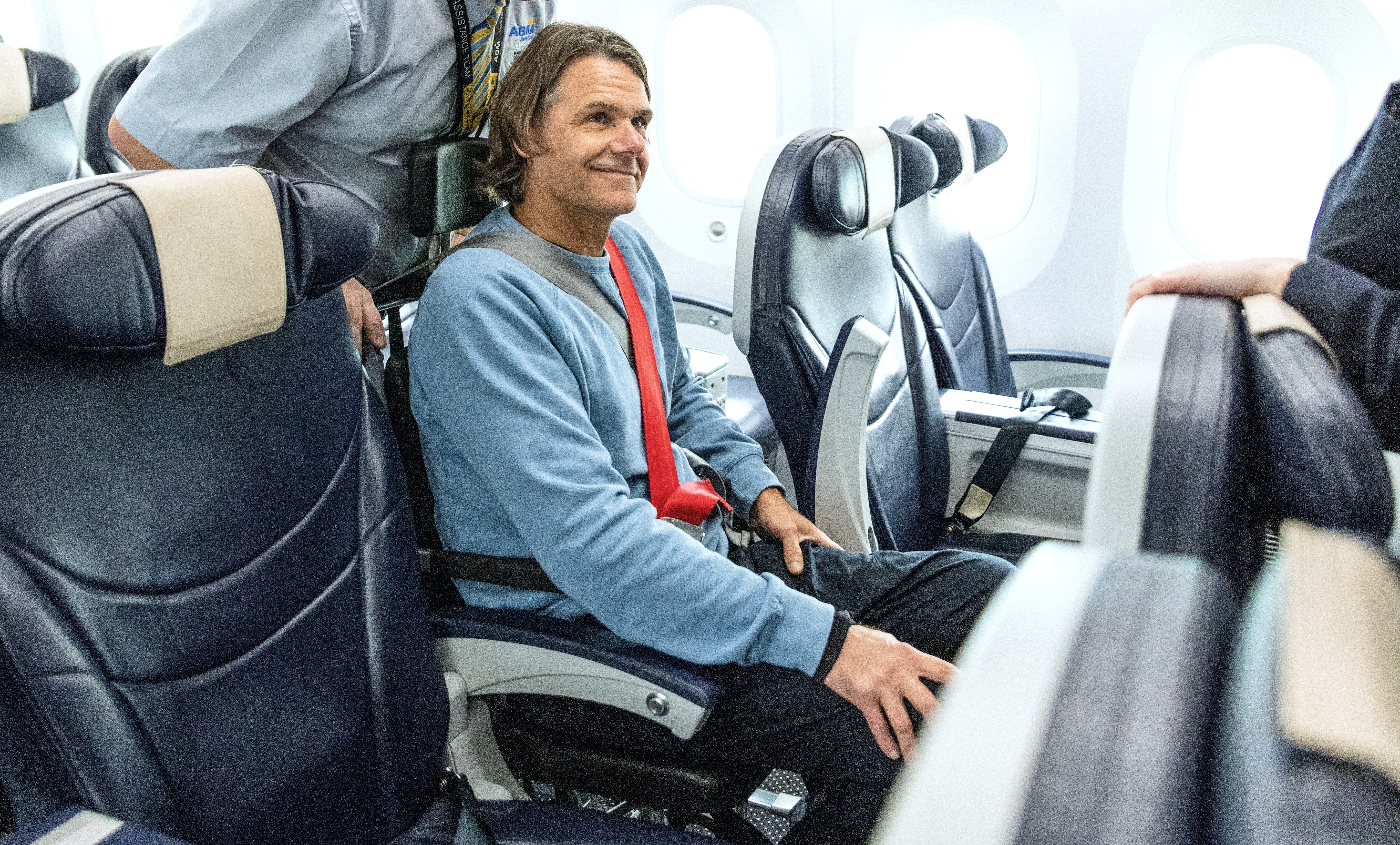Mann i rullestol blir vist til setet sitt på flyet.