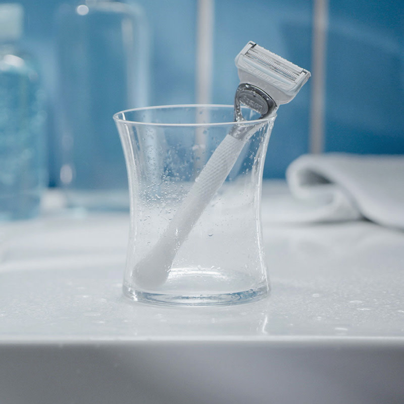 Gillette Venus Pubic rakhyvel placerad i ett glas, inne i ett badrum
