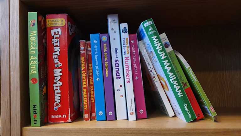Kuva useammasta lasten kirjasta kirjahyllyssä.