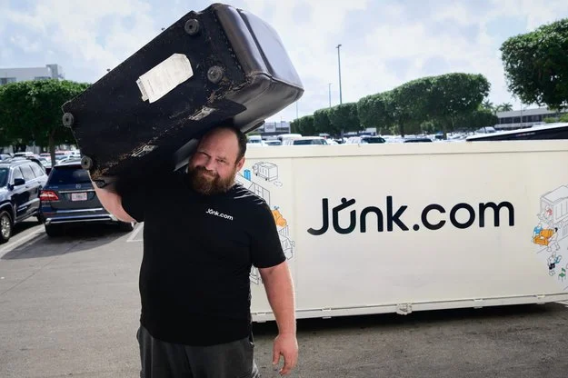 Expert junk hauler from Junk.com takes an old couch away from the Junk.com truck bed.