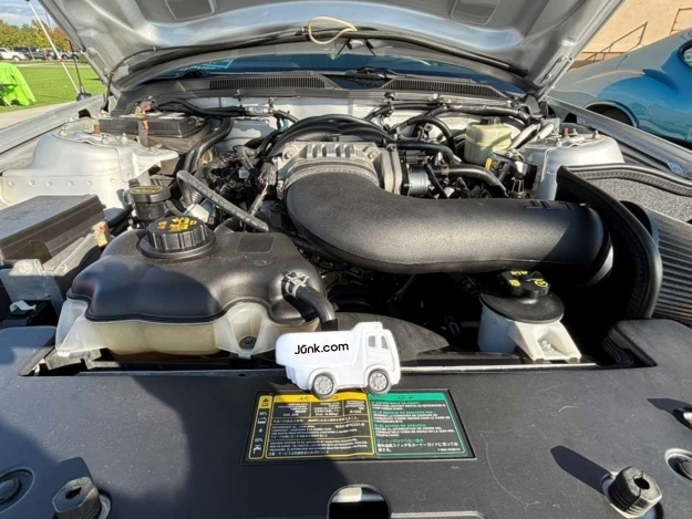 Under the hood of a classic car at the Pueblo Ridez N Rodz car show where a squishy Junk.com stress toy sits.