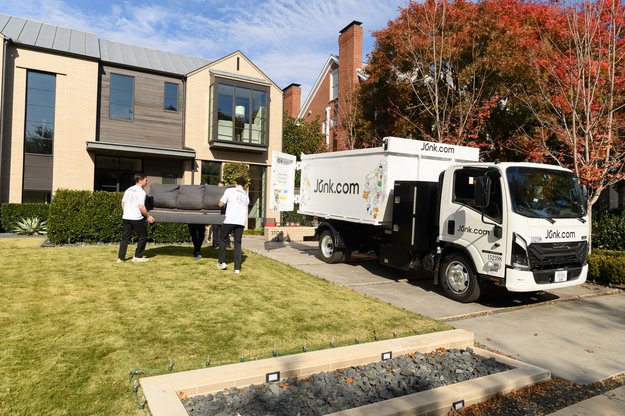 Junk haulers take office couch out to the Junk.com truck for ethical disposal.