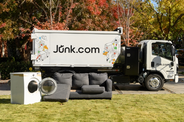 Junk.com truck sits in a residential driveway with a couch and a washer to be hauled away for sustainable disposal like donation and recycling.