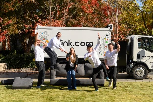 Junk.com removal team poses on a junked couch in front of the Junk.com removal truck.