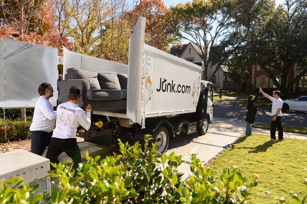 Junk removal crew loads old couch and furniture into a junk truck for donation to a local charity. 