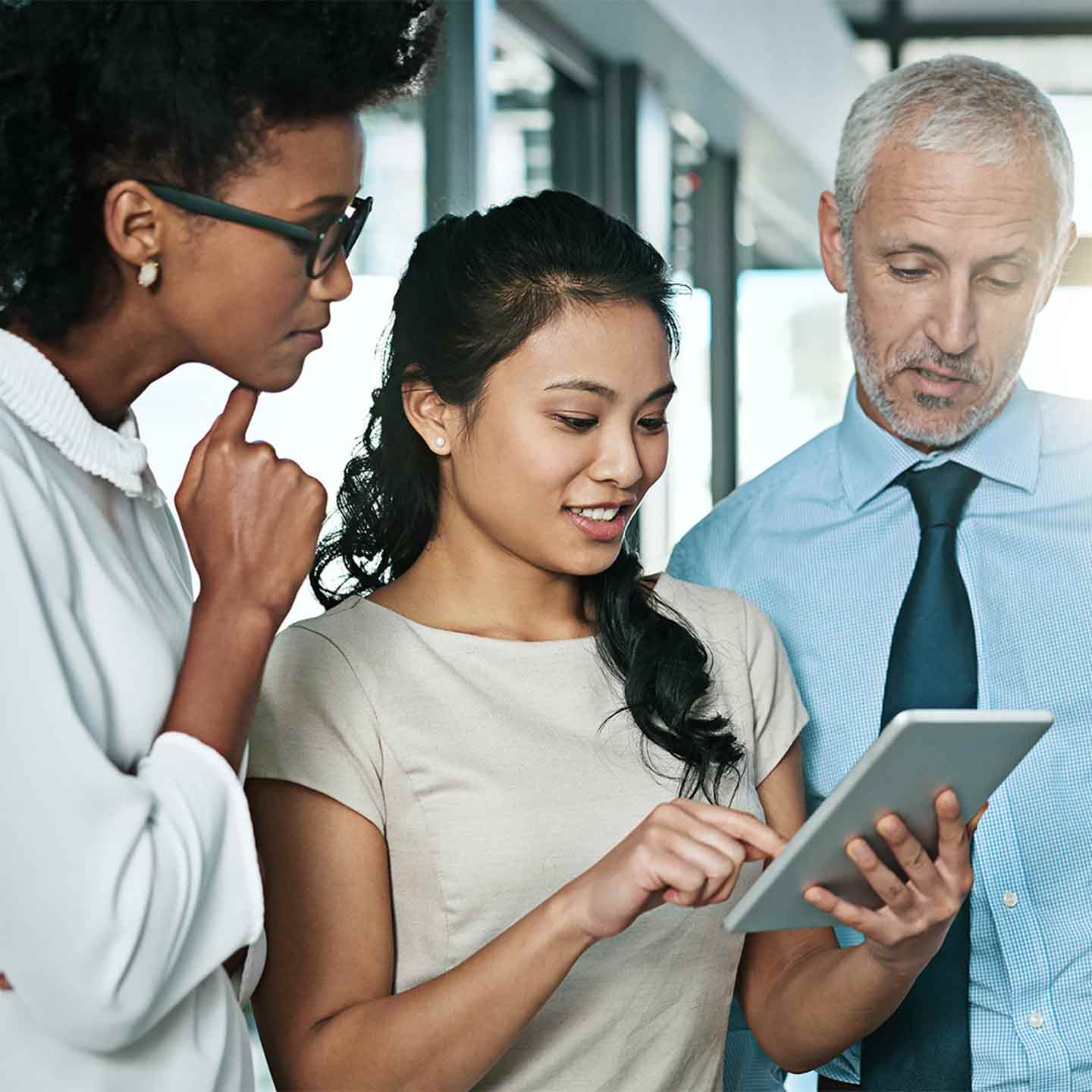 three professionals looking at a tablet in an office building