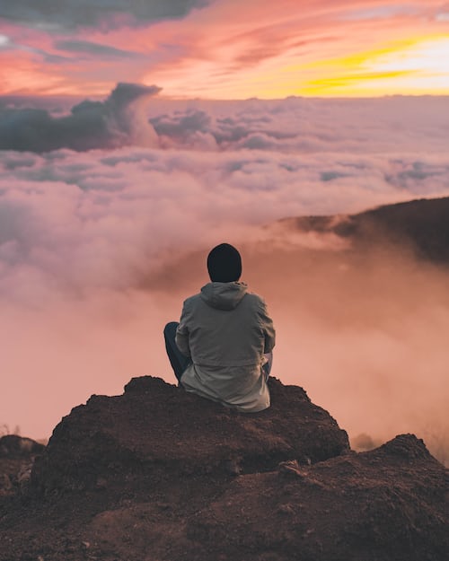A man meditating on the edge of a mountain with great view