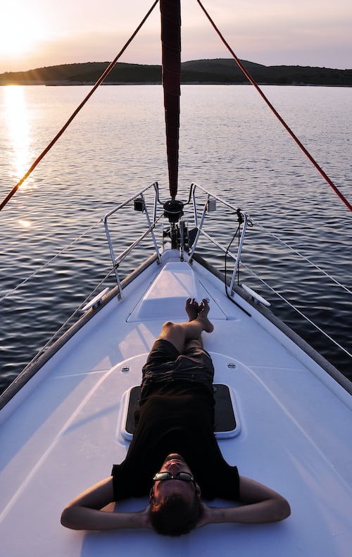 Man laying on the deck of a boat relaxing