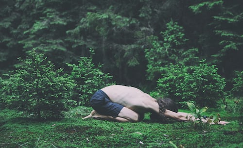 A man lying on the ground in the forest.