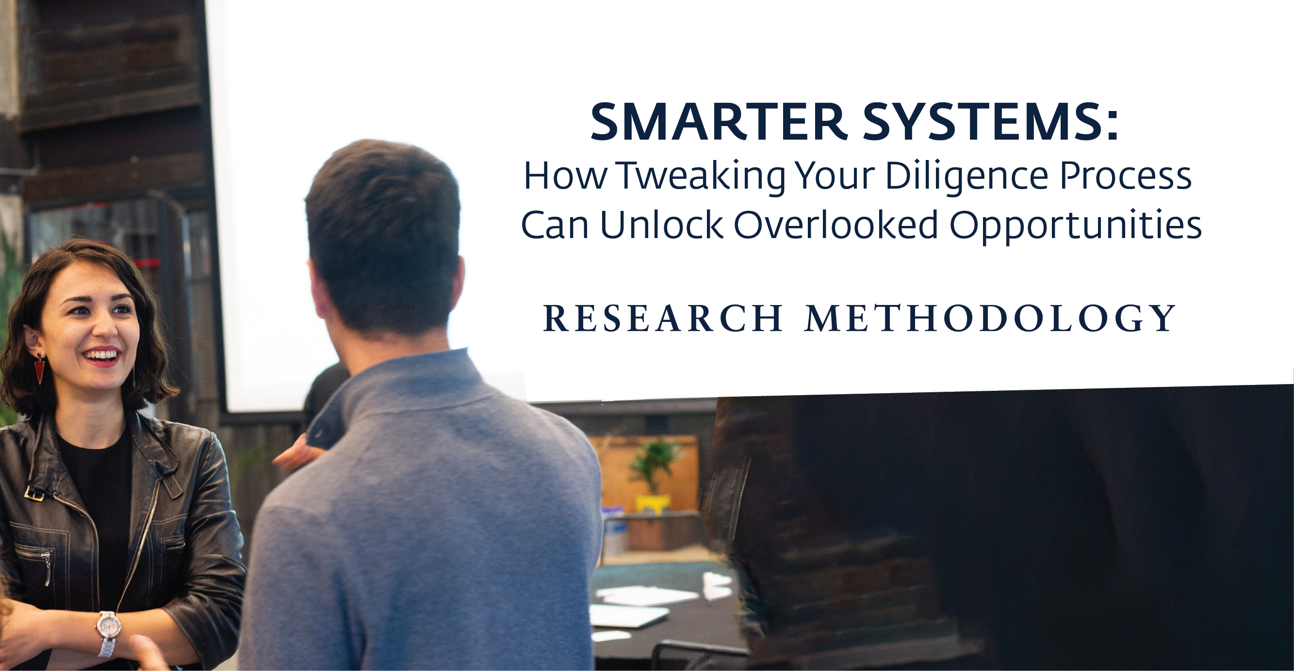 Two people are conversing in a professional setting with a presentation slide in the background that reads, Smarter Systems: How Tweaking Your Diligence Process Can Unlock Overlooked Opportunities. Research Methodology.