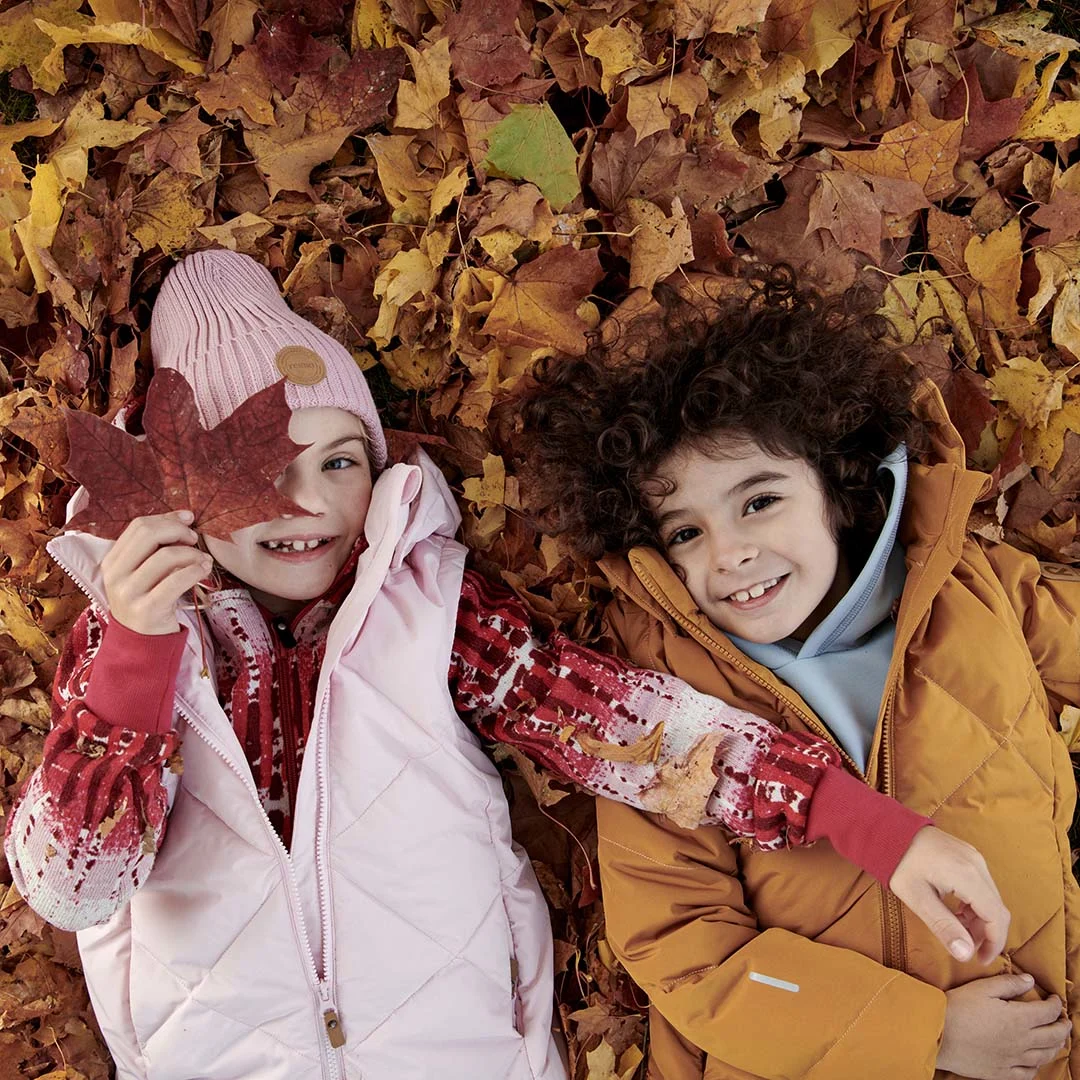 kids-laying-in-leaves-wearing-warm-jackets